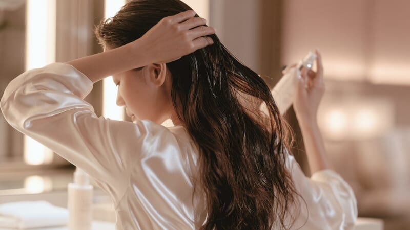 ドレッサー前でヘアケアする女性